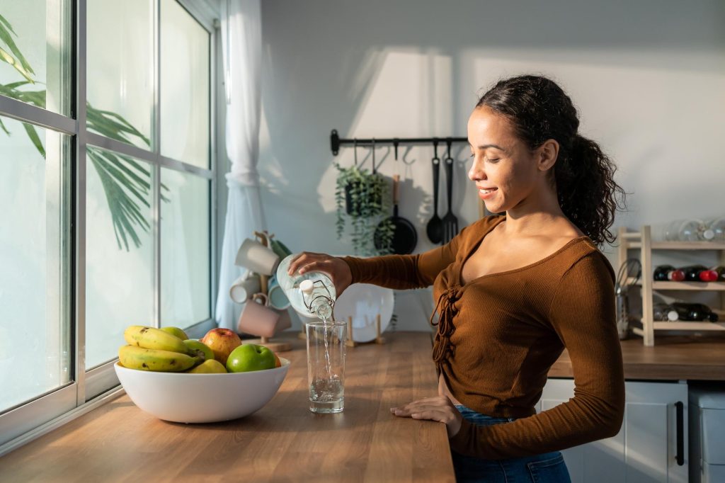 Une femme qui boit de l'eau dans sa cuisine